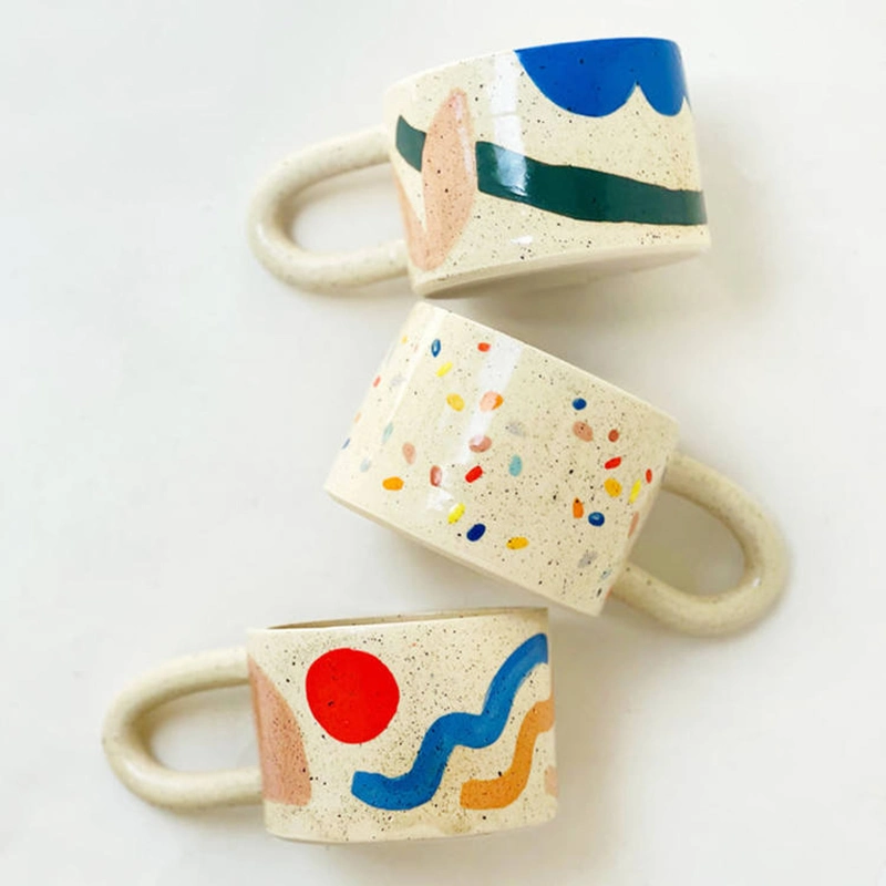 Caneca de café ou chá com alça gordinha e estilosa, com estampa pontilhada colorida de bolinhas, seguindo a tendência estética contemporânea nórdica.