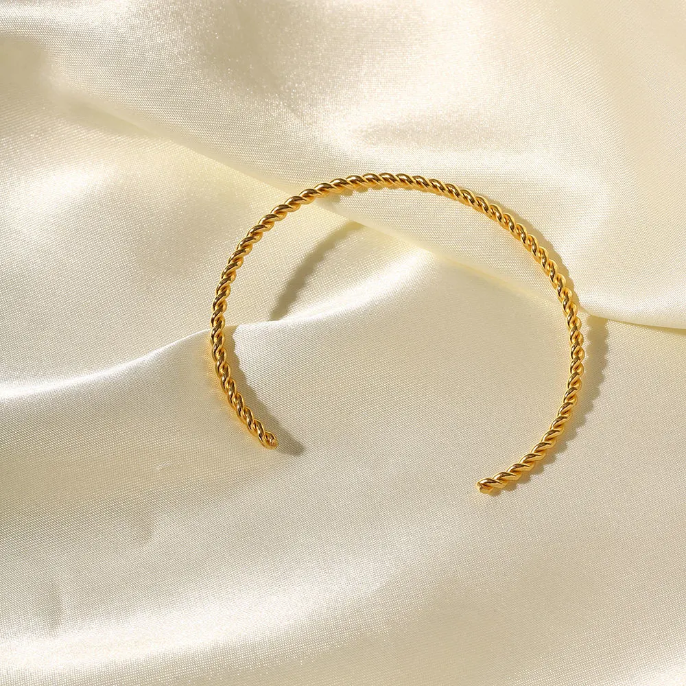 Bracelet fin en acier inoxydable plaqué or 18 carats et étanche avec ouverture torsadée.
