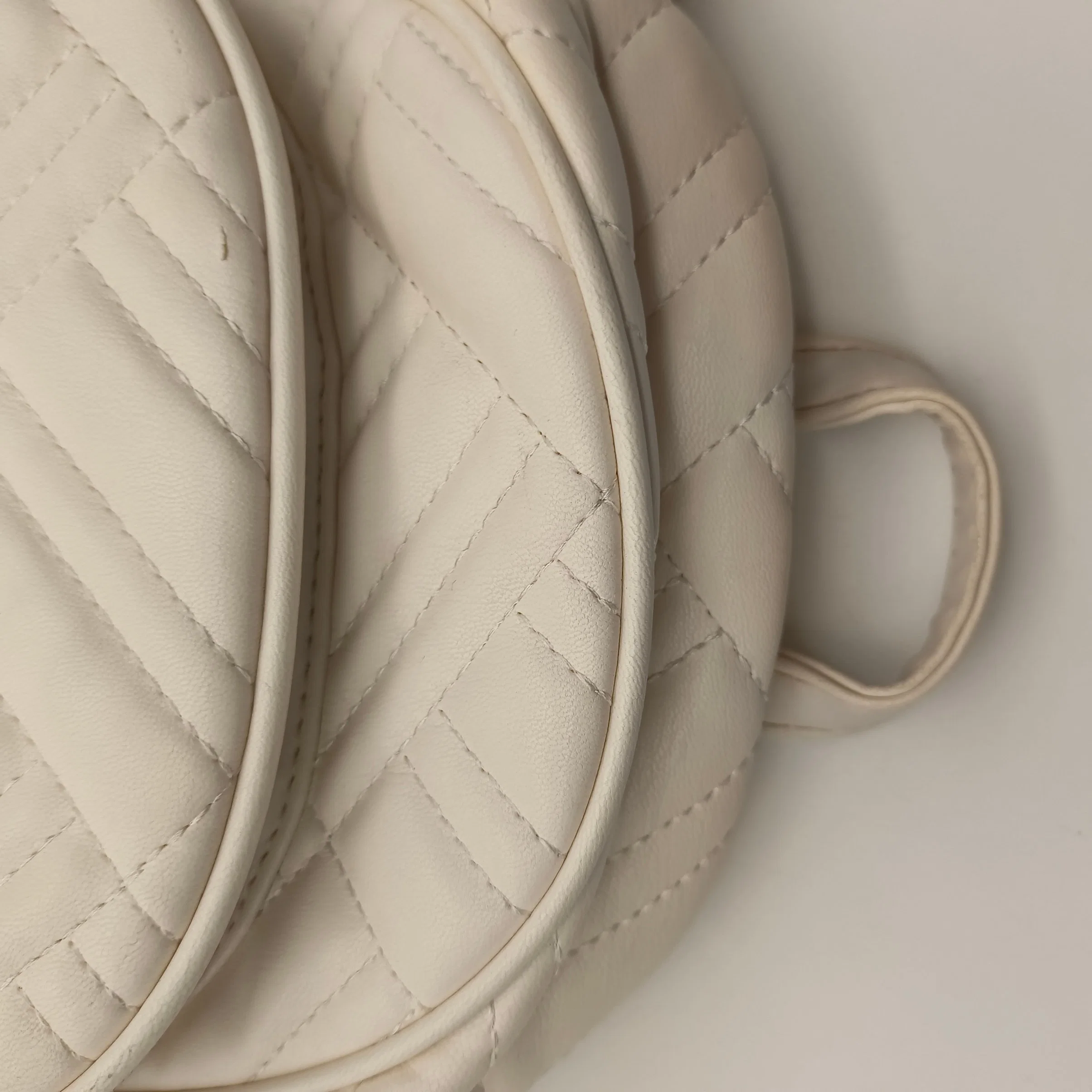 The Beige Semi Circular Diamond Sewn PU Backpack Has Multiple Layers of Pockets.