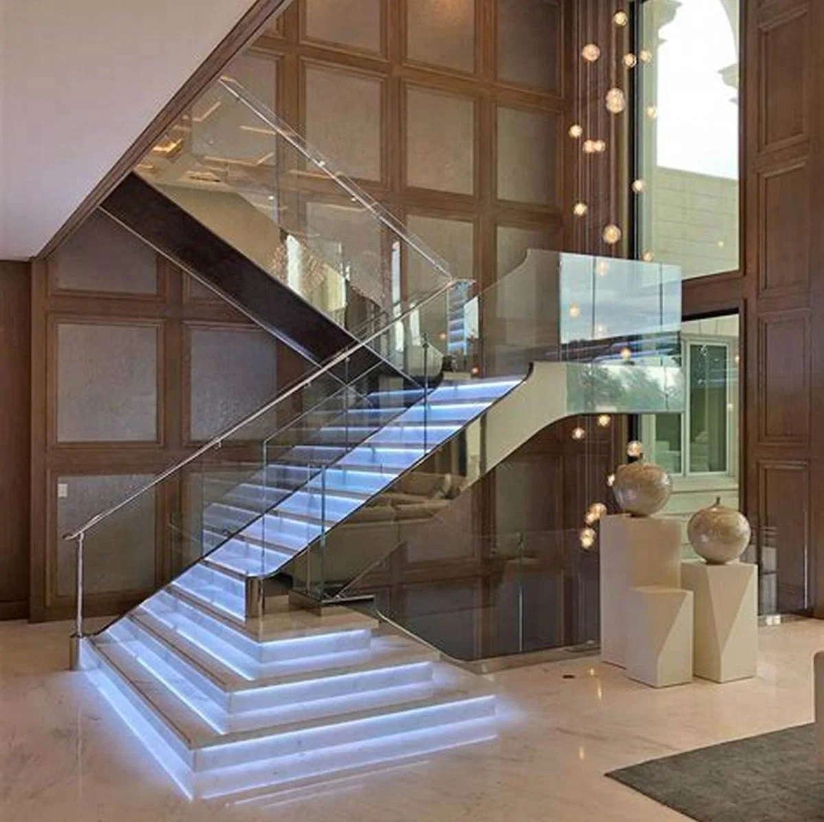 Escalier en marbre avec finition miroir en acier inoxydable, design en forme de U avec rampe en verre.