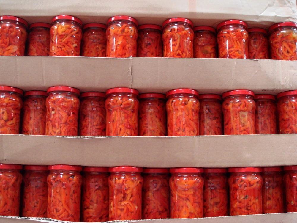 Las mitades de pimiento rojo dulce en el frasco de vidrio