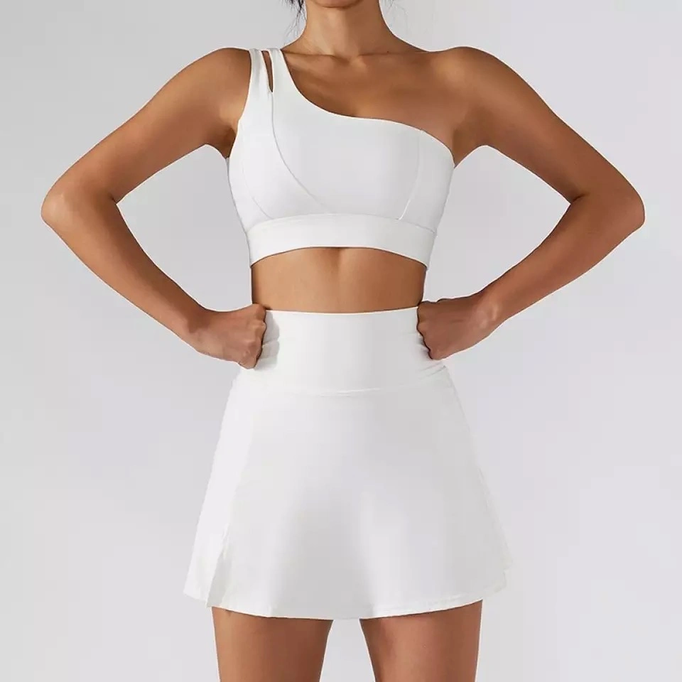 Ensemble de vêtements de tennis, badminton, golf et softball pour femmes, de qualité supérieure, doux, mignon et sexy en gros. Personnalisé avec un soutien-gorge à une épaule et une jupe athlétique 2 en 1.