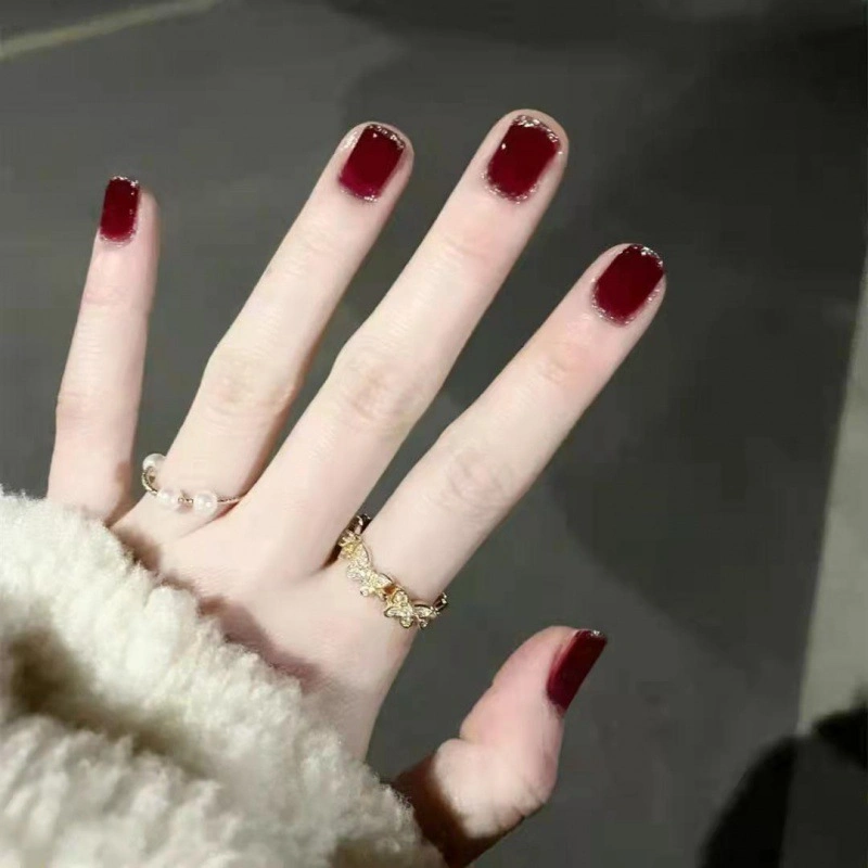 Les correctifs d'ongles rouge bord d'argent au trésor de presse sur le clou de MANUCURE Beauté produit.