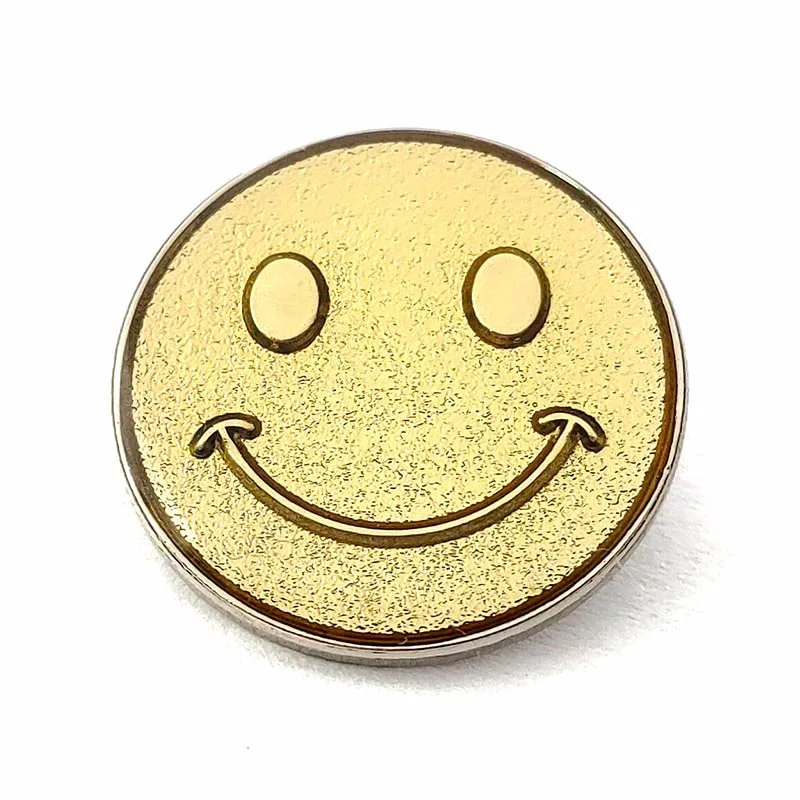 In French, the translation of "Gold Plated Sanded Metal Craft Souvenir Smiley Face Pin Badge" is "Insigne de broche en métal sablé plaqué or, souvenir d'artisanat avec un visage souriant".