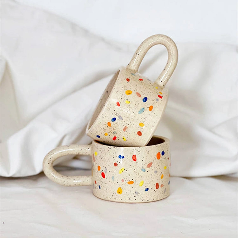 Caneca de café ou chá com alça gordinha e estilosa, com estampa pontilhada colorida de bolinhas, seguindo a tendência estética contemporânea nórdica.